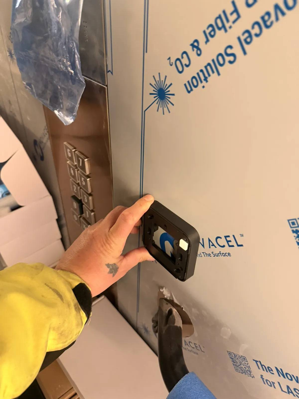 Technieker monteert een lezer naast het bedieningspaneel van een lift